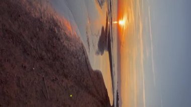 Vertical video, sunset on a deserted beach by the sea.