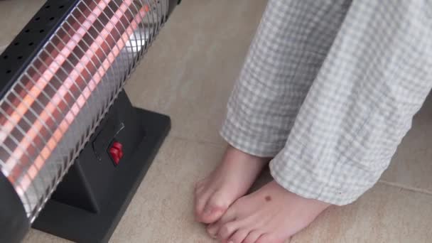 Ένα Παιδί Ζεσταίνει Πόδια Του Μια Ηλεκτρονική Μπαταρία Στο Σπίτι — Αρχείο Βίντεο