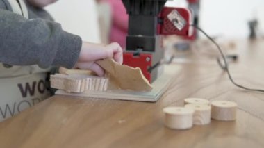 Bir çocuk marangozluk atölyesinde ahşap tavşan yapar. Oyun kulübünde tahta tavşanı olan çocuk elleri.