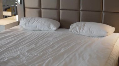 A tired female tourist falls on a bed in a hotel.