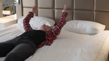 A tired female tourist lies on the bed in the hotel.