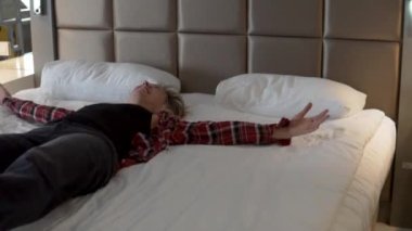 A happy woman from the run falls on the bed in the hotel after the excursion.