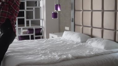 A happy tourist jumps on the bed from a run-up, slow-motion shooting, a hotel room in Turkey.