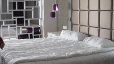 A woman is a traveler lying down on the bed in clothes, slow-motion filming.