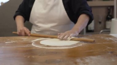 A woman rolls out thinly the dough with a rolling pin. National Turkish dish, Dinner at the hotel of Turkey