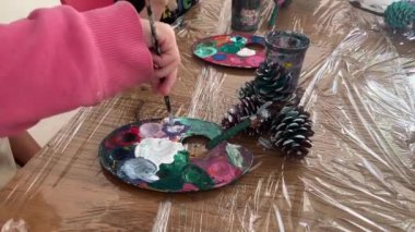 Close-up, a little girl mixes paints in a palette.