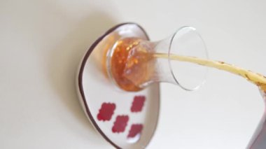 Vertical video, A man pours black Turkish tea into a glass cup.