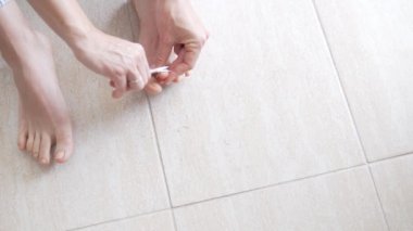 A woman pulls up her toenails with manicure scissors, close-up.