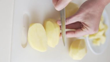 Close-up, a womans hand cuts a knife into cubes.