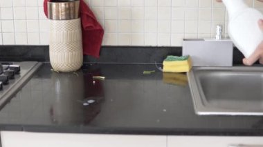 Bir kadın mutfak tezgahındaki kiri temizliyor..