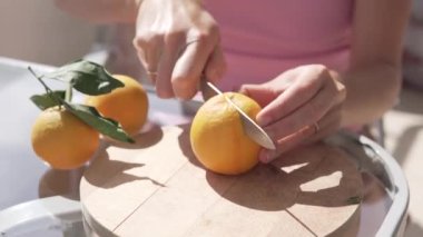 Yakından bakınca, bir adamın elleri portakalı tahta bir parlatıcıyla kesiyor..