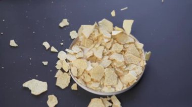 Reflü patates cipsleri siyah arka planda bir tabağa dökülüyor, şık bir stüdyo videosu..