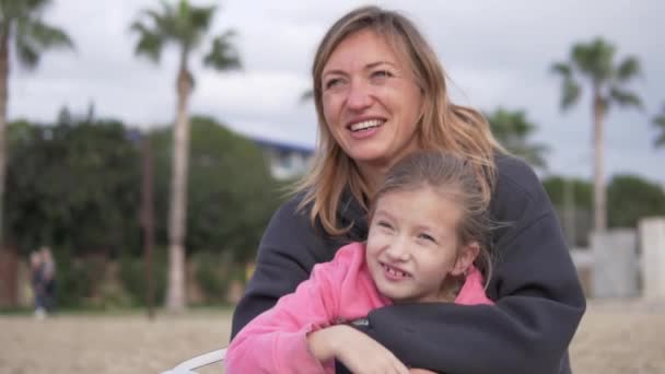 一个女人在海滩上抱着一个反复无常的女儿 — 图库视频影像