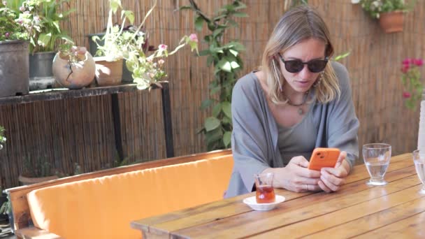 夏のレストランのテーブルで携帯電話を使用してサングラスの美しい観光客の女性 トルコ — ストック動画