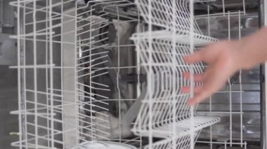 Bir kadın evdeki bulaşık makinesine kirli bulaşıkları koyuyor. Dikey video