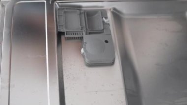 El bulaşık makinesine bir tablet deterjan koyar, yakın plan..