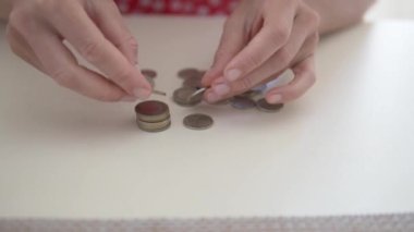Yakın plan, kadınların elleri masada metal paraları sayıyor. Kadın sikkeleri naminal, Türk lirası ve enflasyona göre ayırıyor.