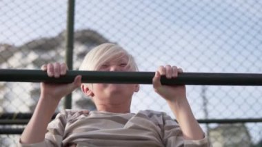 Çekici genç evin avlusundaki yatay çubuğa yanaşıyor. Yazın bahçede aletsiz çocuklar için spor aktiviteleri konsepti.