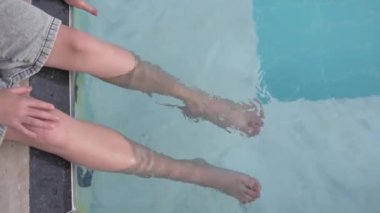 Yazın bir çocuk havuzda ayaklarını ıslatır. Bacaklarını kapat.