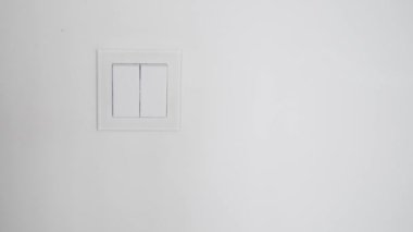 Bir kadının eli odadaki sarı ışığı yakar..