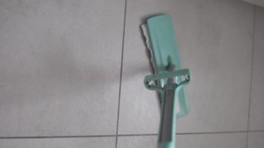 Dikey video, ıslak mendilli paspasın yakın çekimi, bir apartmanın zemininde fayansları yıkamak..