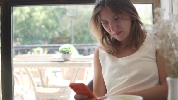 Μια Γυναίκα Ένα Τηλέφωνο Στο Χέρι Κάθεται Στο Παράθυρο Μιας — Αρχείο Βίντεο