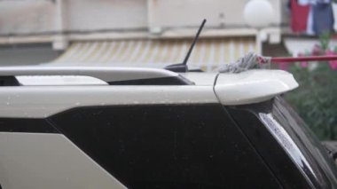 Yakın plan, bir adam yazın evin yakınında bir paspasla arabanın çatısını yıkıyor..