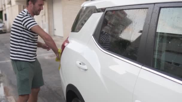 夏に家の近くで車を洗っているハンサムな男 車に焦点を当てる 男はぼやけた — ストック動画