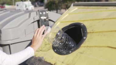Yakın çekim, ayrı çöp ayıklama, plastik şişeyi çöp kutusuna atan ve ona el sallayan kadın..
