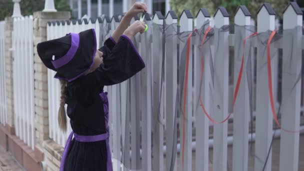 Een Meisje Een Kostuum Versiert Het Hek Met Zwarte Doek — Stockvideo