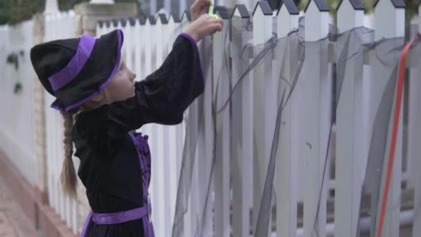 Dziewczyna Kostiumie Zdobi Ogrodzenie Domu Czarną Szmatką Święto Halloween — Wideo stockowe