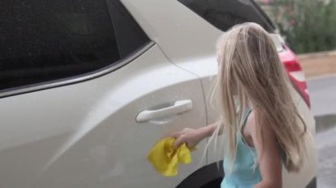 Küçük bir kız yazın İspanya 'da bir evin bahçesinde beyaz bir araba yıkar, Alicante..