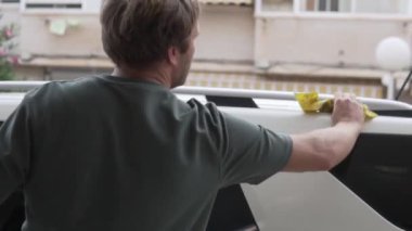 Yazın bir adam evinin bahçesinde arabasını yıkıyor, İspanya, Alicante..