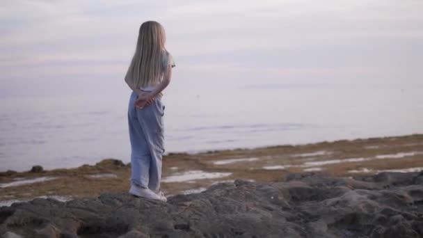 Dziewczyna Długimi Włosami Stoi Skalistej Plaży Patrząc Ocean Wiatr Macha — Wideo stockowe