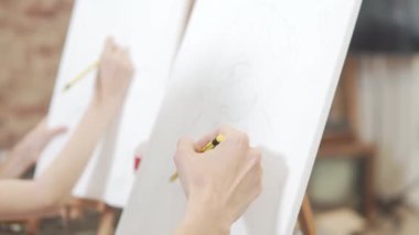 Sanat okulu çizim dersi, öğrenciler beyaz bir tuval üzerinde kalem çizimleri yapıyor. Yakın plan..