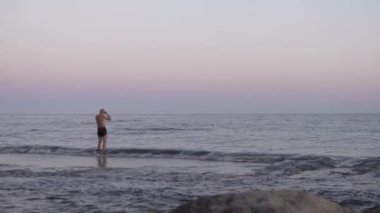 Doğanın, gün batımında kayalık kıyılara çarpan dalgaların olduğu sinematik bir video. Görüntülerde okyanusta, kayada ve sörf tahtasında denizlerin enginliği ve gücü vurgulanıyor.