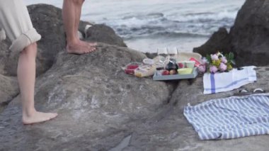 Kız, deniz kenarında güzel bir şekilde yerleştirilmiş yiyecek ve çiçeklerin fotoğrafını çekiyor. Aşık bir çiftle romantik bir akşam..