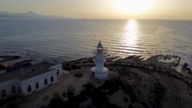 Gün batımında deniz fenerinin arkaplanına karşı yukarıdan bir kuadkopterden çekilen görüntüsü. Günbatımı Deniz Feneri Üstgeçidi, İspanya, Alicante, Yaz 2024