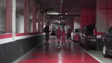 14 Ağustos 2024, İspanya, Alicante. Bir baba ve çocuklar yeraltı otoparkındaki arabaya gidiyor..