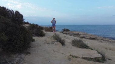 Atletik kadın sabahları deniz kıyısında koşuyor. İspanya, Alicante.