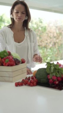 Güzel bir kadın beslenme uzmanı çiftlik sebzelerinin kalitesini kontrol eder ve diyet için bir ürün listesi yazar. İspanya, Alicante, dikey video