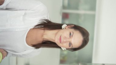 Gülümseyen güzel kadın kozmetiğin tadını çıkarıyor. Dikey video, bir kadın yüzüne avokado getiriyor..