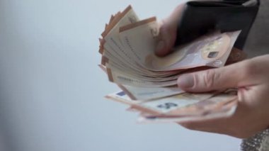 Yakın plan, 50 avroluk banknotları sayan kadın elleri ve parayı siyah bir cüzdana koyuyor..