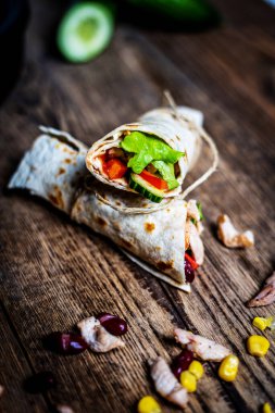 Geleneksel Meksika tortilla dürümü ve ahşap masada tavuk eti ve sebze.