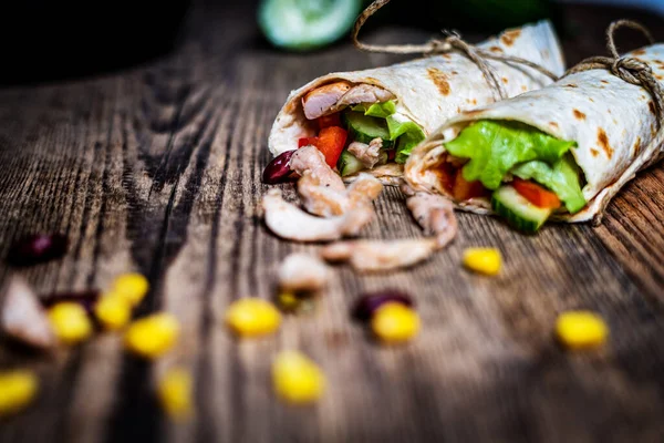 Geleneksel Meksika tortilla dürümü ve ahşap masada tavuk eti ve sebze.