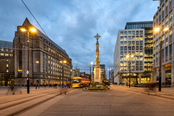 Трамвай метро, проходящий рядом с крестом Святого Петра на площади Святого Петра в ратуше Манчестера, Англия