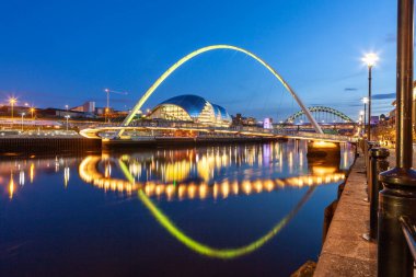 Newcastle Quayside 'daki Milenyum Köprüsü akşam güneşiyle aydınlandı ve Tyne nehrine yansıdı.