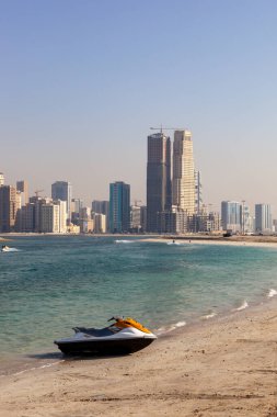 Sharjah Sahili. Deniz kıyısı motorlu, şehir mimarisi arka planda.