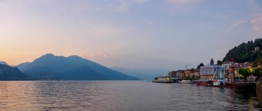 Como Gölü 'nde huzurlu bir akşam. Bellagio şehri manzaralı. Sakin sular, canlı günbatımını yansıtıyor, resim gibi ve sakin bir atmosfer yaratıyor..