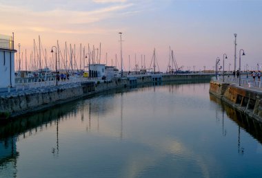 Senigallia, İtalya: yat ve teknelerin üzerinde gün batımındaki liman manzarası. Şehir manzarası. Şehir kartpostalı. Alacakaranlıkta Marina
